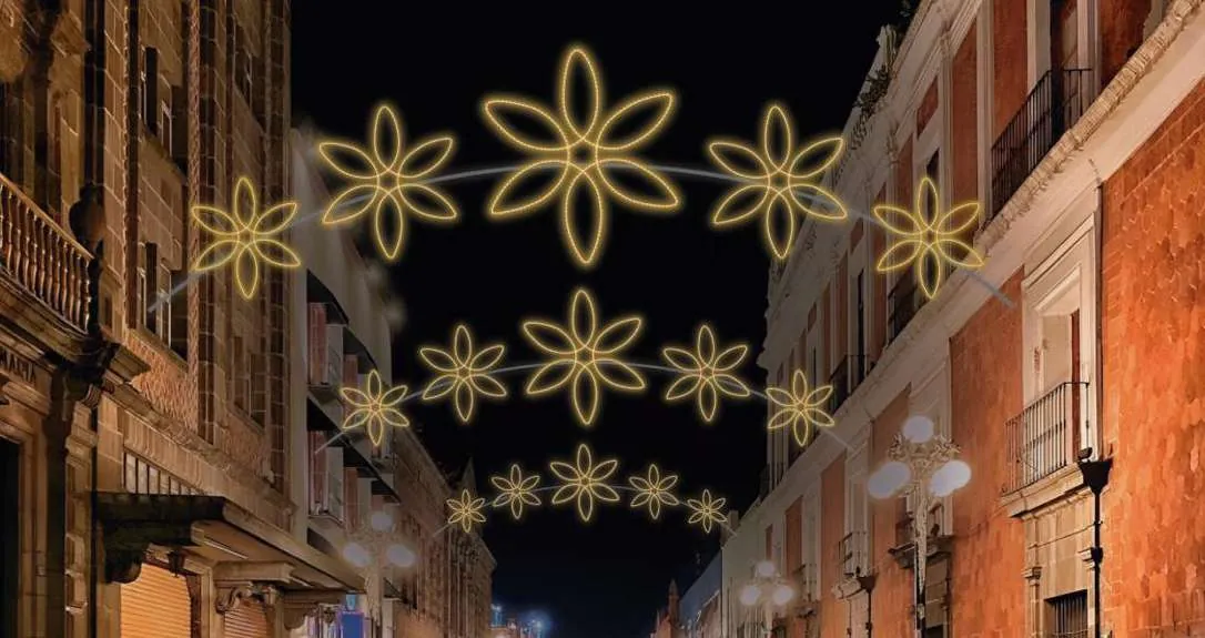 Pasacalle de flores doradas de luz cruzando una calle histórica