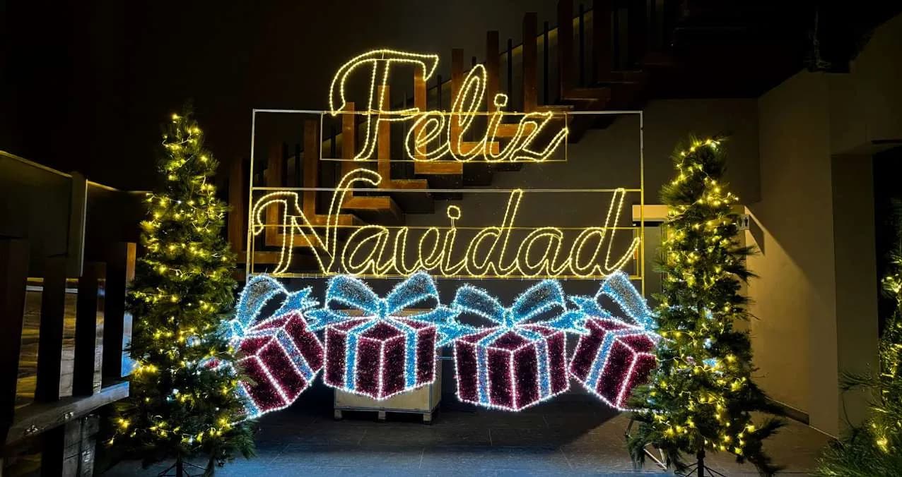 Montaje de letras 'Feliz Navidad' con regalos iluminados para evento