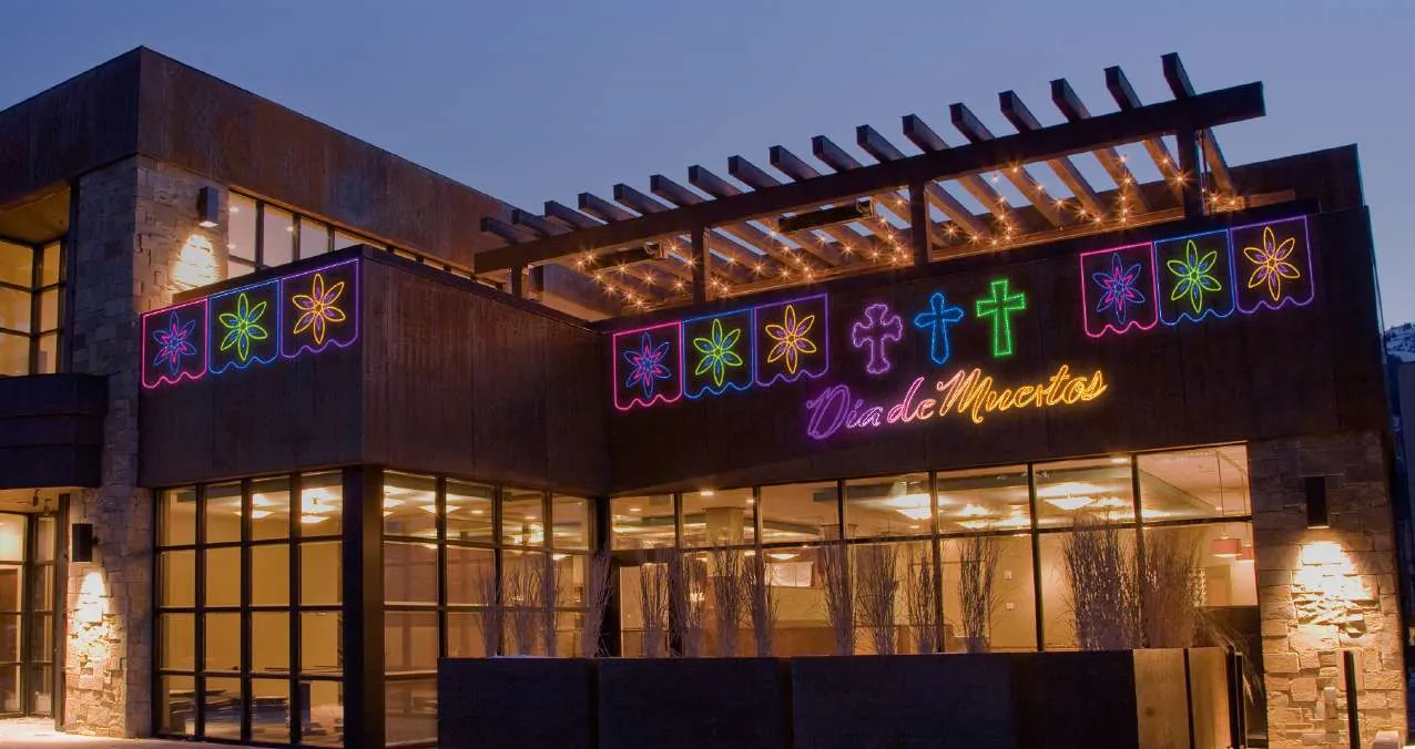 Edificio con decoración de Día de Muertos en neón: papel picado, cruces y catrinas
