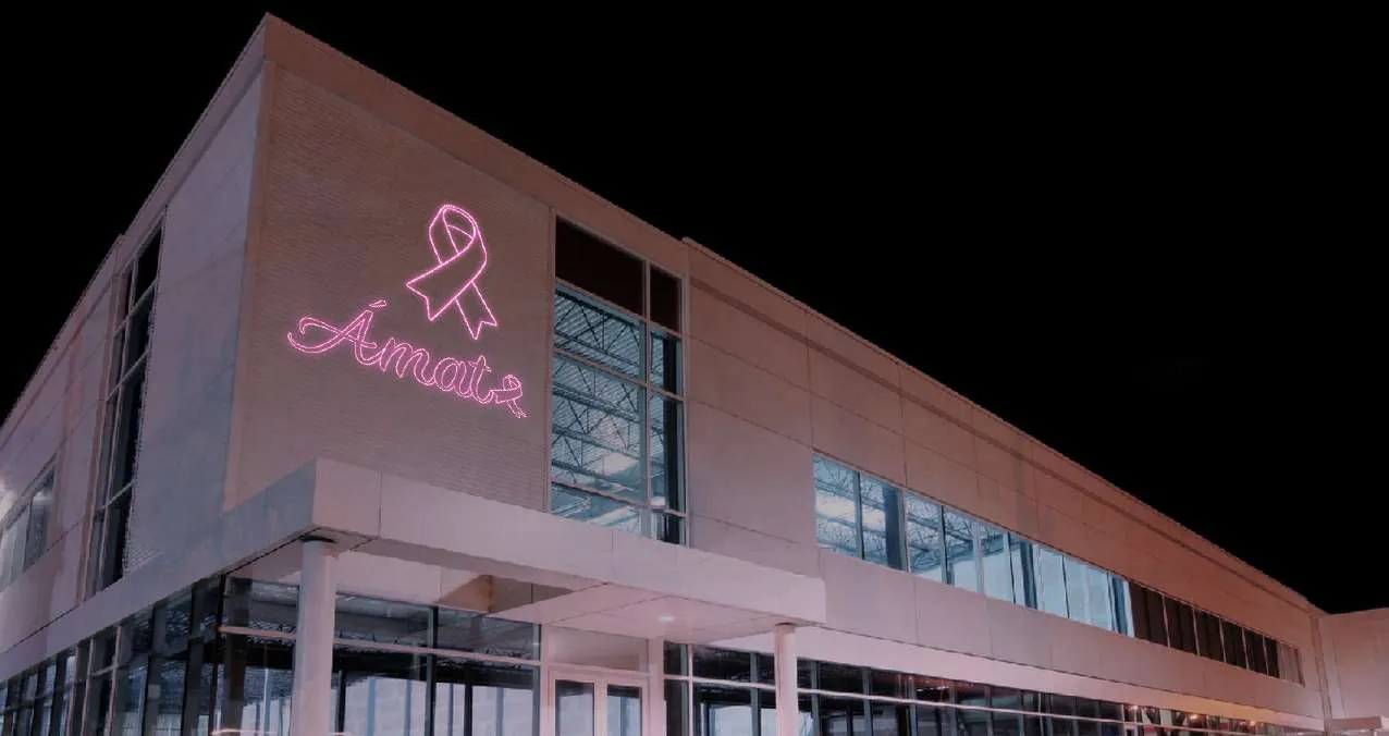 Fachada con lazo y letrero 'Ámate' en luz rosa por Octubre Rosa